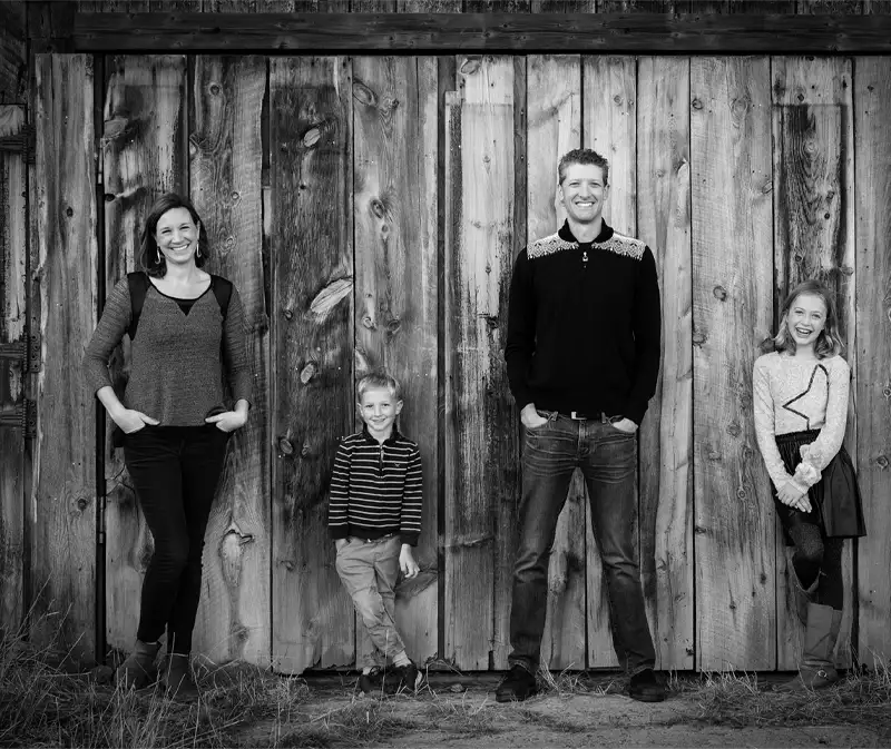Dr. Isaac Mooberry and his family standing outdoors against a wooden backdrop, presenting a professional and family-oriented image.